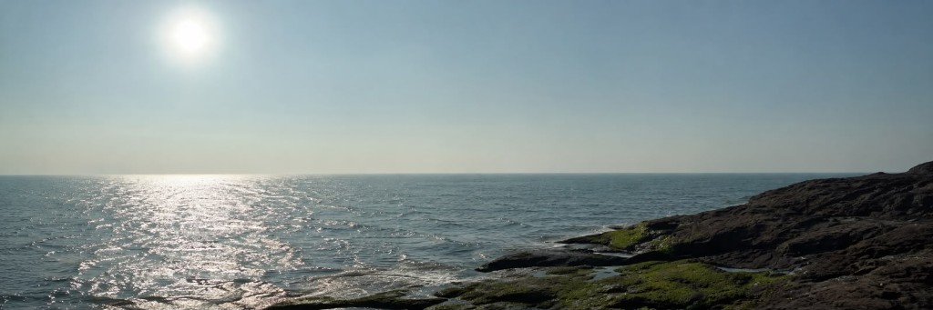 Rocky shoreline — sun on water, fading horizon