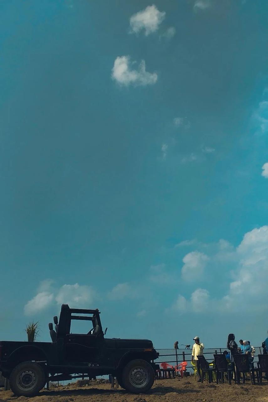 A jeep against open sky — hilltop viewpoint, drifting clouds
